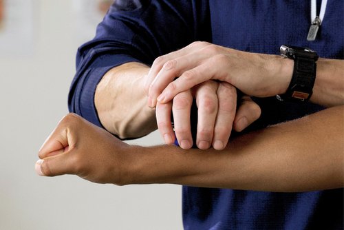 A man gently holds the wrist of another person, conveying a sense of connection and support between them.