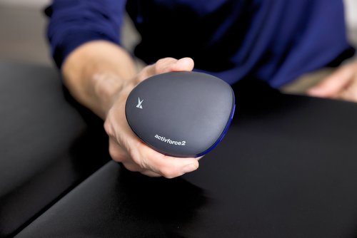  A person holding a small device while seated at a table, focused on the task at hand.