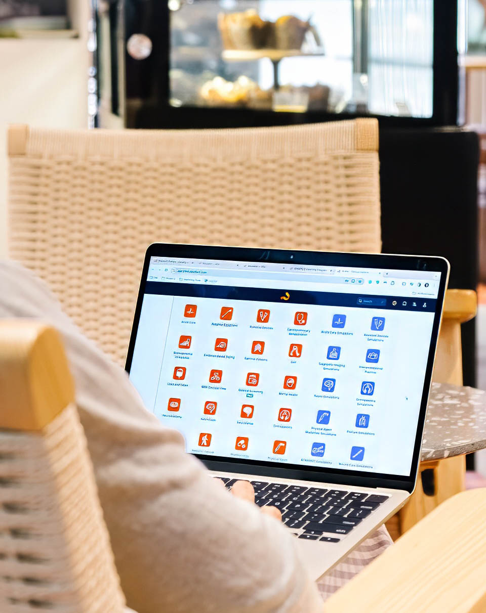 A person holding a laptop while seated at a table, focused on the task at hand